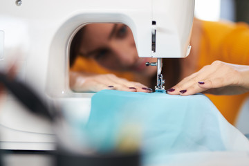 Close up of smiling caucasian seamstress sewing beautiful evening dress.