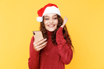 Happy santa girl with mobile in the red sweater isolated