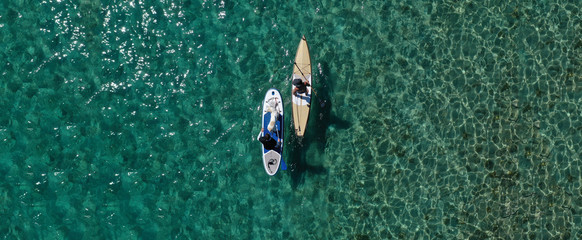 Aerial drone ultra wide panoramic photo of unidentified fit man paddling with his cute dog on a SUP...