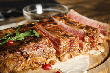 Delicious grilled ribs on wooden board, closeup