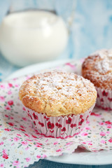 Close-up of two homemade lemon muffins with a jug of milk, selective focus
