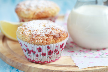 Close-up of two homemade lemon muffins with a jug of milk, selective focus