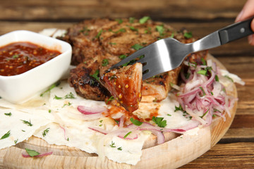Fork with piece of delicious grilled meat, closeup
