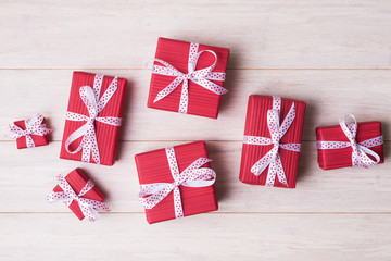 Obraz premium Red gift boxes with spotted bows over light wooden background with copy space