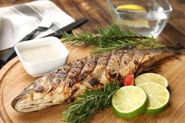 Delicious grilled fish with lime on wooden board, closeup