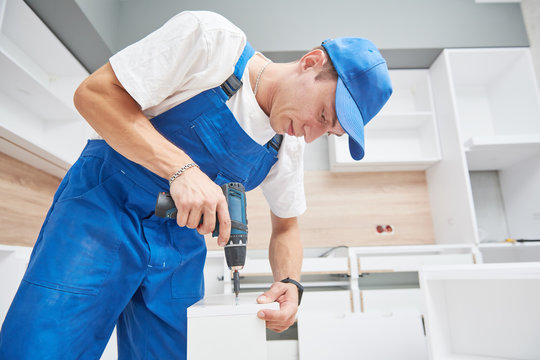 kitchen installation. Worker assembling furniture