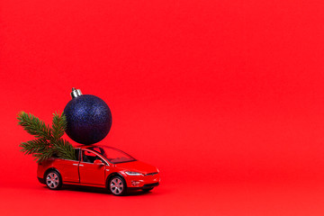 Christmas background. Red toy car with Christmas tree fir branch and blue navy decoration bauble...
