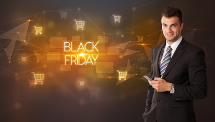 Businessman with shopping cart icons and BLACK FRIDAY inscription, online shopping concept