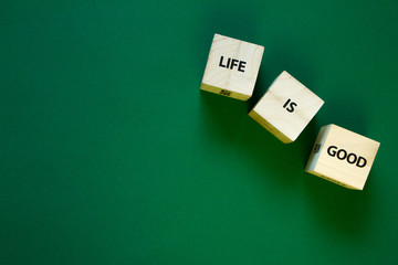 Life is good words on the faces of wooden cubes on a green background, selective focus