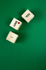 I love you words on the faces of wooden cubes on a green background, selective focus
