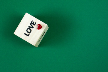 Word Love on the face of wooden cube on a green background, selective focus
