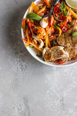 Fototapeta na wymiar Buddha bowl lunch with grilled chicken and carrot, red bell pepper, onion, rice and herbs on light grey stone background. Healthy balanced eating. Comfort food.