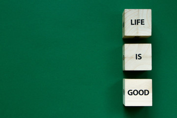 Life is good words on the faces of wooden cubes on a green background, selective focus