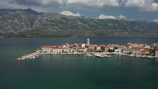 Swimmers enjoy quiet old town marina in midday sun, advancing aerial