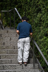 A Japanese business man with a blue shirt and a white trouser walks on a stairway in Osaka-Japan.