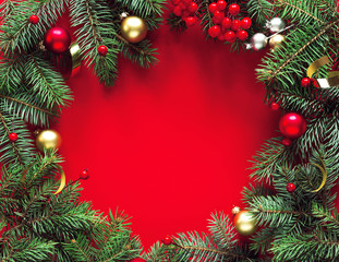 Fototapeta na wymiar Round frame of fir branches and holiday decorations on a red background, top view with space for text. Christmas winter background, christmas card.