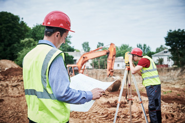 Construction workers on building area. Foreman with blueprint and surveyoor