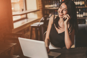 Business woman working on a laptop and using phone in a cafe.