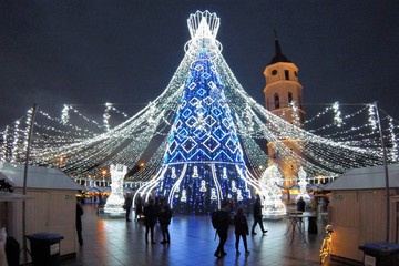 Beautiful Christmas tree decorated with white and blue lights for Christmas 2019 and New Year 2020, market and celebrations in Vilnius Cathedral square, evening 