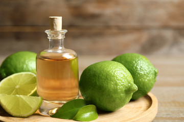 Lime essential oil and citrus fruits on wooden table, closeup