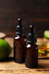 Lime essential oil in bottles on wooden table