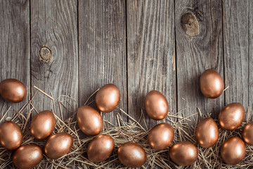 Background with Golden Easter eggs on wooden background.