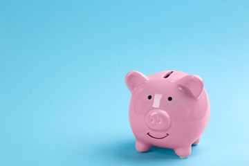 Pink piggy bank on light blue background. Space for text