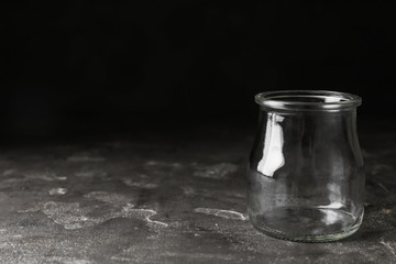Empty glass jar on grey stone table, space for text