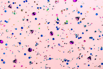 Multi Colored sparkly gemstones on pastel pink background.