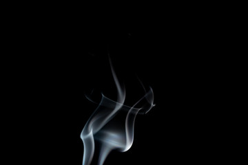 White wavy smoke drifting upwards on a black background