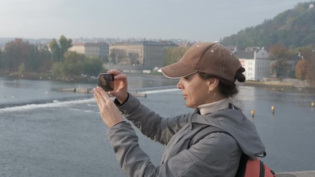 Tourist takes pictures on a smartphone. Girl tourist photographs the embankment and the river.