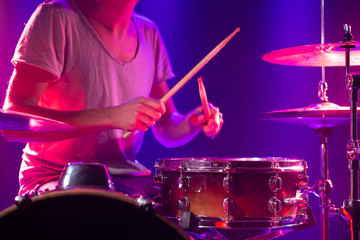The drummer plays the drums. Beautiful blue and red background, with rays of light. Beautiful...