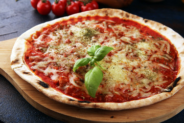 Pizza with tomatoes, mozzarella cheese, basil. Delicious italian pizza on wooden pizza board.