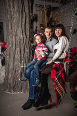 young family on Christmas eve sitting on a swing under a blanket