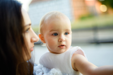 Happy mother and daughter in the park. Beauty nature scene with family outdoor lifestyle. Happy family resting together on the green grass, having fun outdoor. Happiness and harmony in family life
