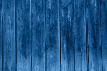 The back wall of the old barn in classic blue color tone. Background of old boards.