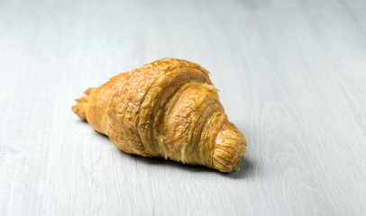 Freshly plain croissant on a bright wooden surface