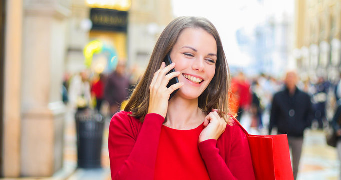 Young woman shopping with a Christmas outfit while walking and speaking on the phone