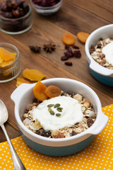 Oat flakes with nuts, dried fruit mix in bowl over rustic wooden table, isolated. Healthy breakfast food.
