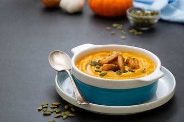 Pumpkin soup in a bowl,with fresh pumpkin seeds. Autumn foods. Healthy, vegetarian food, dark background.