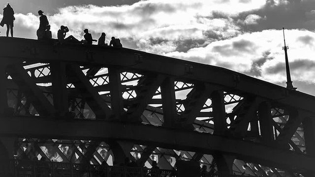 Risky behavior, young people walk and take pictures of each other on top of an old steel bridge,  time lapse