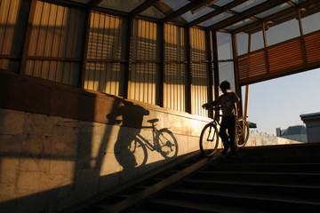 A boy with a bicycle descends into an underground pedestrian crossing