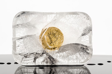 Concept image for cryptocurrency security featuring a gold bitcoin  in a block of ice which is starting to melt.