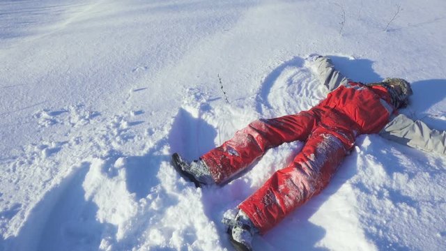 Happy boy on winter park making snow angel