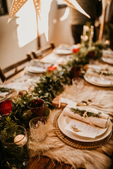 Christmas table setting for traditional lunch or dinner on a rustic table with seasonal greeting cards, tableclothes, tableware and festive decorations. Concept of family traditions and celebrations