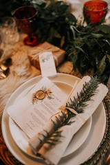 Christmas table setting for traditional lunch or dinner on a rustic table with seasonal greeting cards, tableclothes, tableware and festive decorations. Concept of family traditions and celebrations