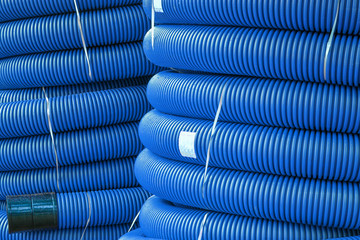 Coils of new red plastic pipe for underground cable protection with rain drops