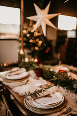 Christmas table setting for traditional lunch or dinner on a rustic table with seasonal greeting cards, tableclothes, tableware and festive decorations. Concept of family traditions and celebrations