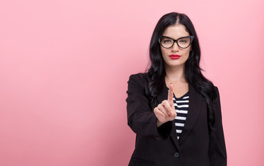 Young woman pointing at something on a pink background