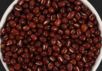 Red adzuki beans in a bowl on black background